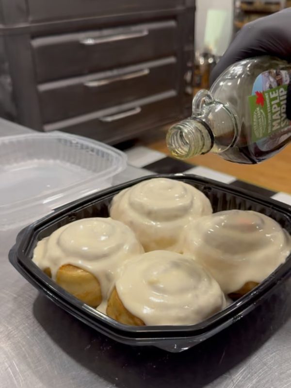 Cinnamon buns topped with icing and maple syrup, prepared french toast style