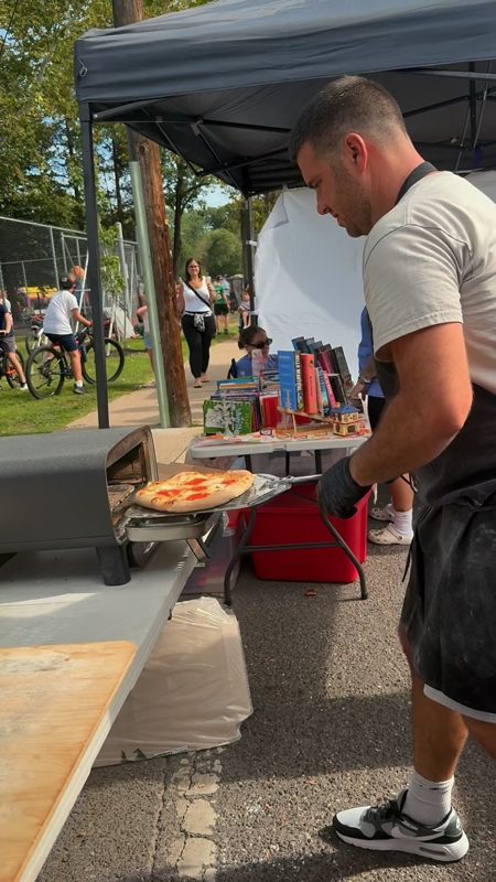 Video still of sliding a pizza into a portable oven at an outdoor private event